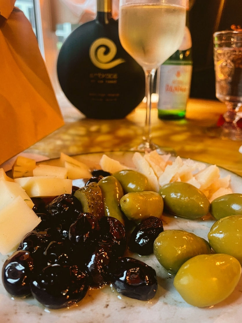 Ein Teller mit Oliven und Käse und einem Glas Wein